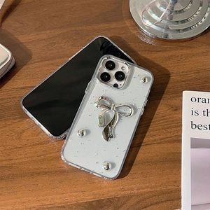 Dettaglio custodia iPhone con fiocco argento 3D e perline su base traslucida glitterata