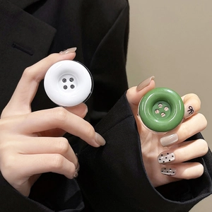 Detailed view of button-shaped phone grip stand in green and white on a lifestyle background