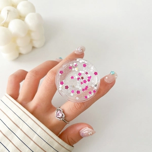 Close-up of glittery pink star and flower sequins inside a round phone socket grip