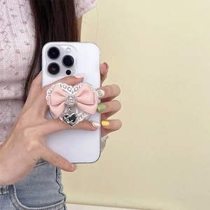 Lace heart phone grip with pink ribbon and metal heart charm on a white smartphone