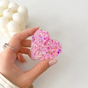 Macro detail of pink glitter heart phone grip with sparkling sequins and resin finish