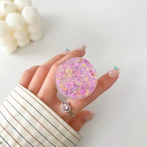 Detail of pink glitter phone socket grip held between fingers with matching heart ring