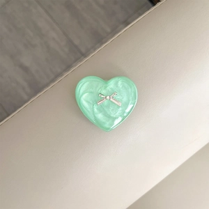 Detail of mint green heart phone socket with pearlescent texture and silver bow accent