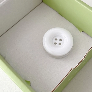 Close-up of white 4-hole round button phone grip with glossy resin finish for easy hold