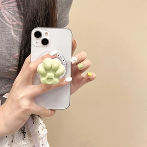 Macro detail of the green cat paw grip attached to a MagSafe ring on a phone.