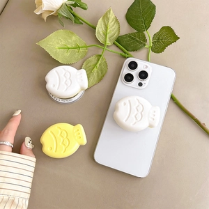 Close-up of matte fish-shaped pop socket holder on smartphone with cream aesthetic decor