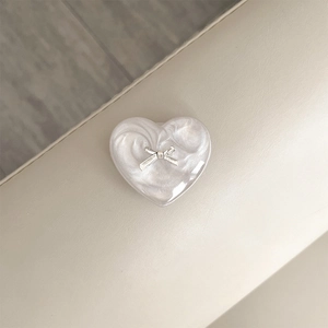 Close-up of a heart-shaped phone grip with pearl texture and a silver bow accent