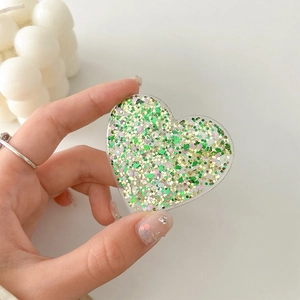 Detail of heart-shaped phone grip with green and gold glitter held by hand