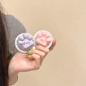Macro detail showing cute matte purple and pink cat paw phone socket stands held in hand.