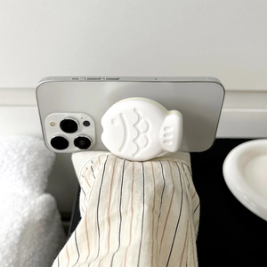 White minimalist fish-shaped phone grip socket with textured scales on a silver smartphone