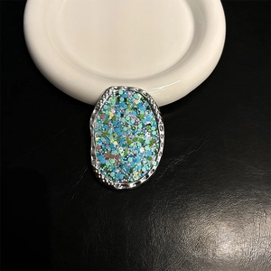 Close-up of oval phone grip with silver hammered metal frame and colorful sequins