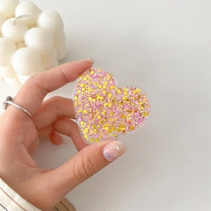 Detail view of heart-shaped glitter phone grip with pink sequins and star confetti
