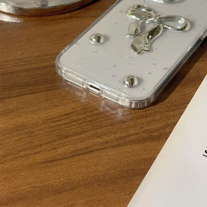 Dettaglio del fiocco in argento e dei rivetti su una custodia per telefono bianca opaca