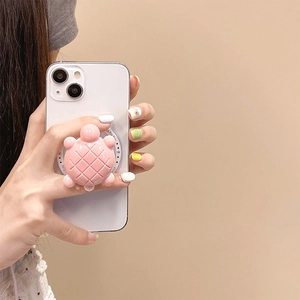 Close-up van een schattige roze 3D-schildpad inklapbare telefoonhouder op een smartphone.