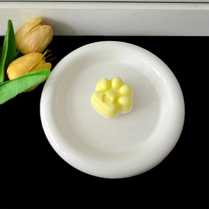 Close-up view of a cute yellow cat paw shaped phone grip with heart detail on a plate