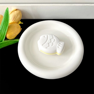 Detailed top view of a white Taiyaki-shaped phone grip with yellow layers on ceramic plate