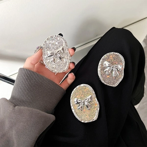 Detail of glitter bow pop socket grip in silver, gold and grey on a smartphone