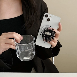 Detail of handmade black beaded phone grip holder featuring a metal handmade engraved tag