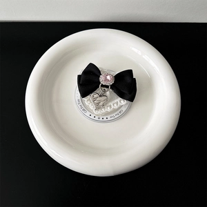 Detail of black silk bow phone stand with pink crystal gem and silver heart pendant