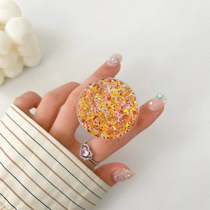 Detail of round expanding phone grip with pink sequins and star-shaped glitter butterfly