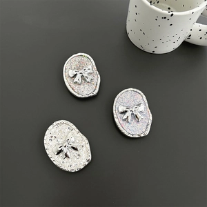 Detail of three glitter oval resin pieces with silver bows for phone grip sockets