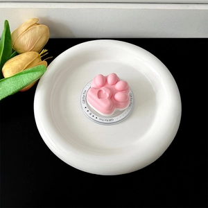 Macro view of the pink cat paw collapsible phone grip resting on a decorative base