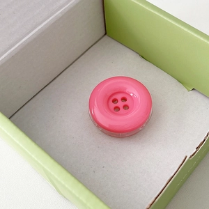 Macro detail of a pink button-style phone grip with a glossy resin finish and four holes