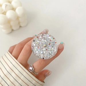 Glittery round collapsible phone socket with silver sequins held by a model