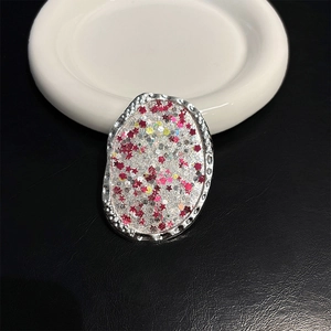 Detail of oval metal phone grip with silver hammered texture and sparkling star sequins