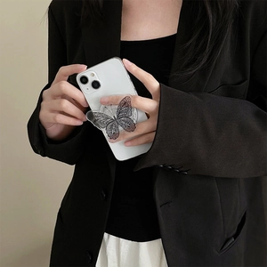 Detail of a black lace butterfly phone grip on a transparent acrylic foldable base