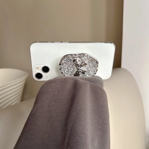 Close-up of glitter silver bow collapsible phone grip stand with shimmering diamond texture