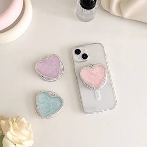 Macro detail of heart-shaped magnetic phone grips with rhinestones in multiple colors