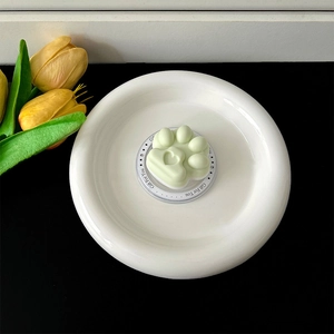 Top-down view of a mint green cat paw phone grip on a white decorative plate.