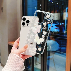 Coque iPhone transparente avec papillons de perles et breloques cœur tenue devant la vitre