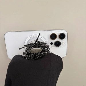Creative black beaded phone grip with handmade metal tag on a white smartphone