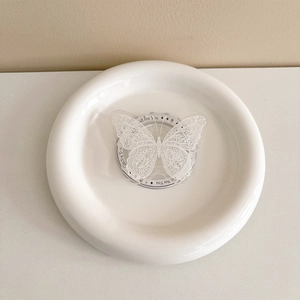 Detailed view of white lace butterfly phone grip on a gift card in a ceramic dish
