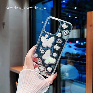 Détail de la coque iPhone transparente avec papillons 3D, perles et paillettes cœur