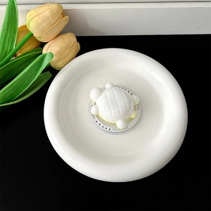 Close-up van een witte 3D-schildpad telefoonhouder op een luxe wit keramisch bord