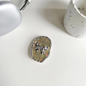 Close-up of a silver bow glitter phone socket on a white desk with aesthetic accessories