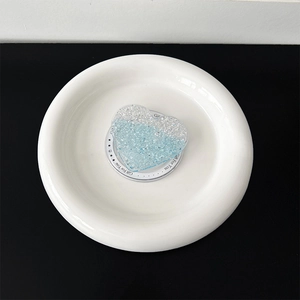 Macro detail of heart-shaped glitter phone grip with Gift For You text on white base