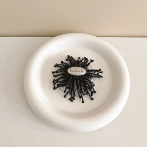Macro detail of handmade metal tag on a black radial floral expanding phone stand