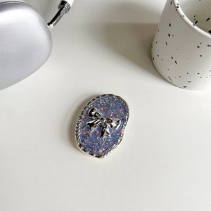 Macro shot of glitter blue resin phone grip featuring a silver 3D bow and wave-textured edge