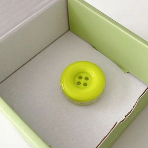 Close-up of lemon green button phone socket grip in minimalist color-matched packaging