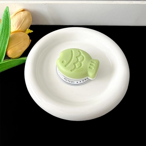 Detail of light green fish-shaped phone grip on a white circular gift base card