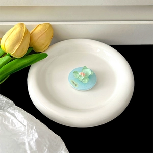 Close-up of a blue magnetic glitter bear phone socket holder on a white ceramic plate