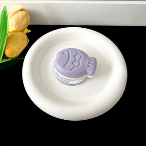 Macro detail of purple fish-shaped phone grip on white gift stand with floral decor