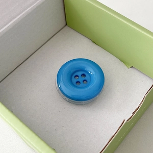 Detail of bright blue button cell phone socket with a transparent base on green box