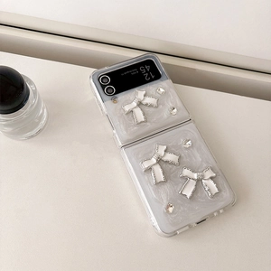 Vue détaillée d'une coque Samsung Z Flip nacrée avec nœuds 3D blancs et strass scintillants