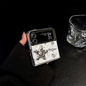 Detail of transparent glitter phone case with metallic starfish and star charms