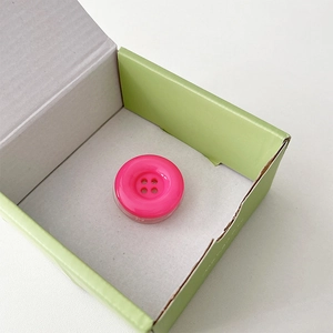 Detail shot of rose red button-shaped phone grip with round four-hole design and transparent base